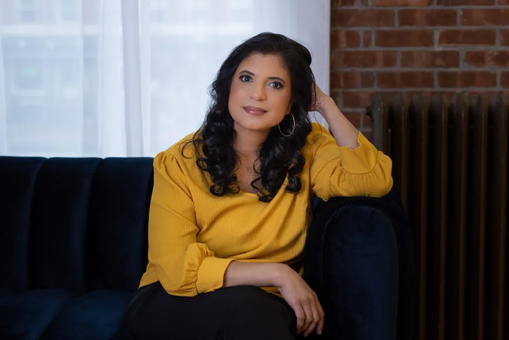 Dr. Ramani on velvet sofa, serene pose in stylish room.